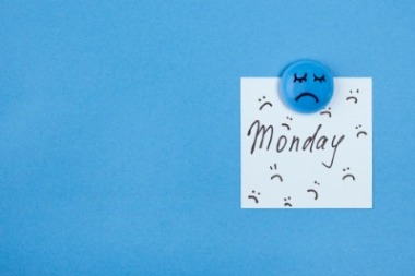 A note about Monday pinned to a blue board, surrounded by sad face illustrations, representing the Monday blues.