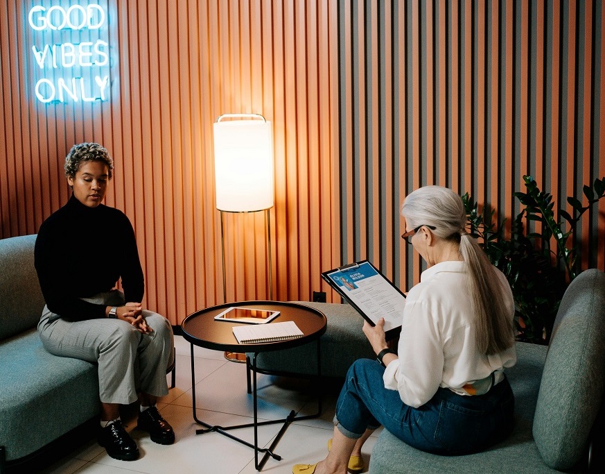 Two women engaged in conversation while seated in a cozy room, sharing thoughts and ideas with one another.