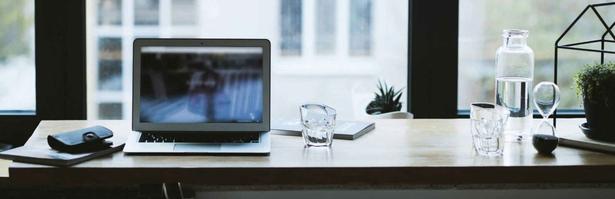  A laptop placed on a desk, positioned near a window, allowing natural light to illuminate the workspace.