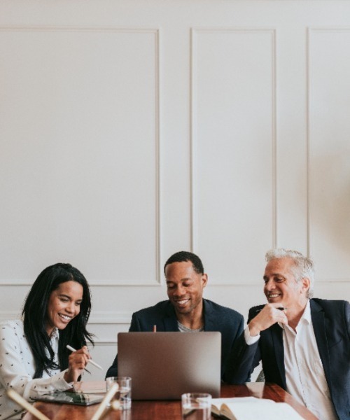 a diverse woman and two men looking at a laptop