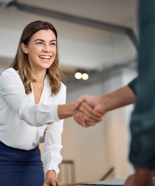 woman shaking another's hand in a professional setting