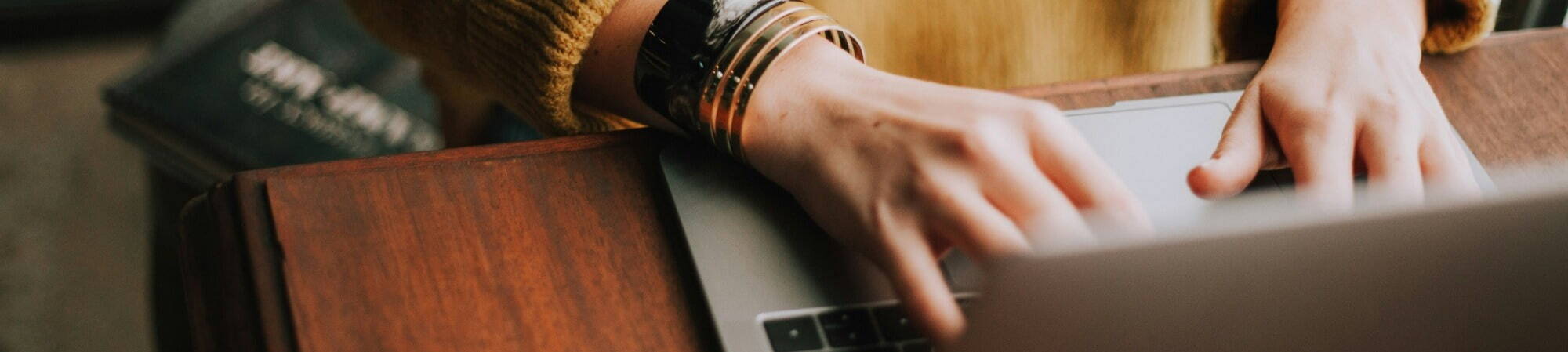 Woman in yellow jumper submitting finance job on laptop.