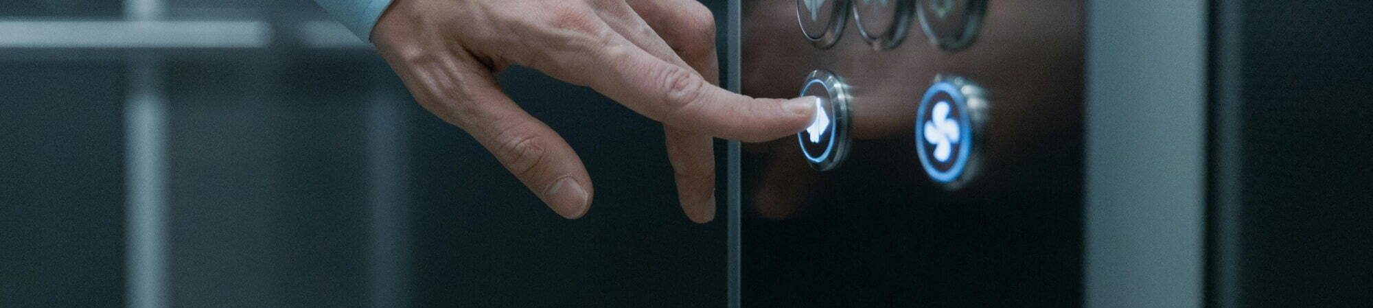 A person pressing the buttons inside an elevator, indicating their desired floor selection.